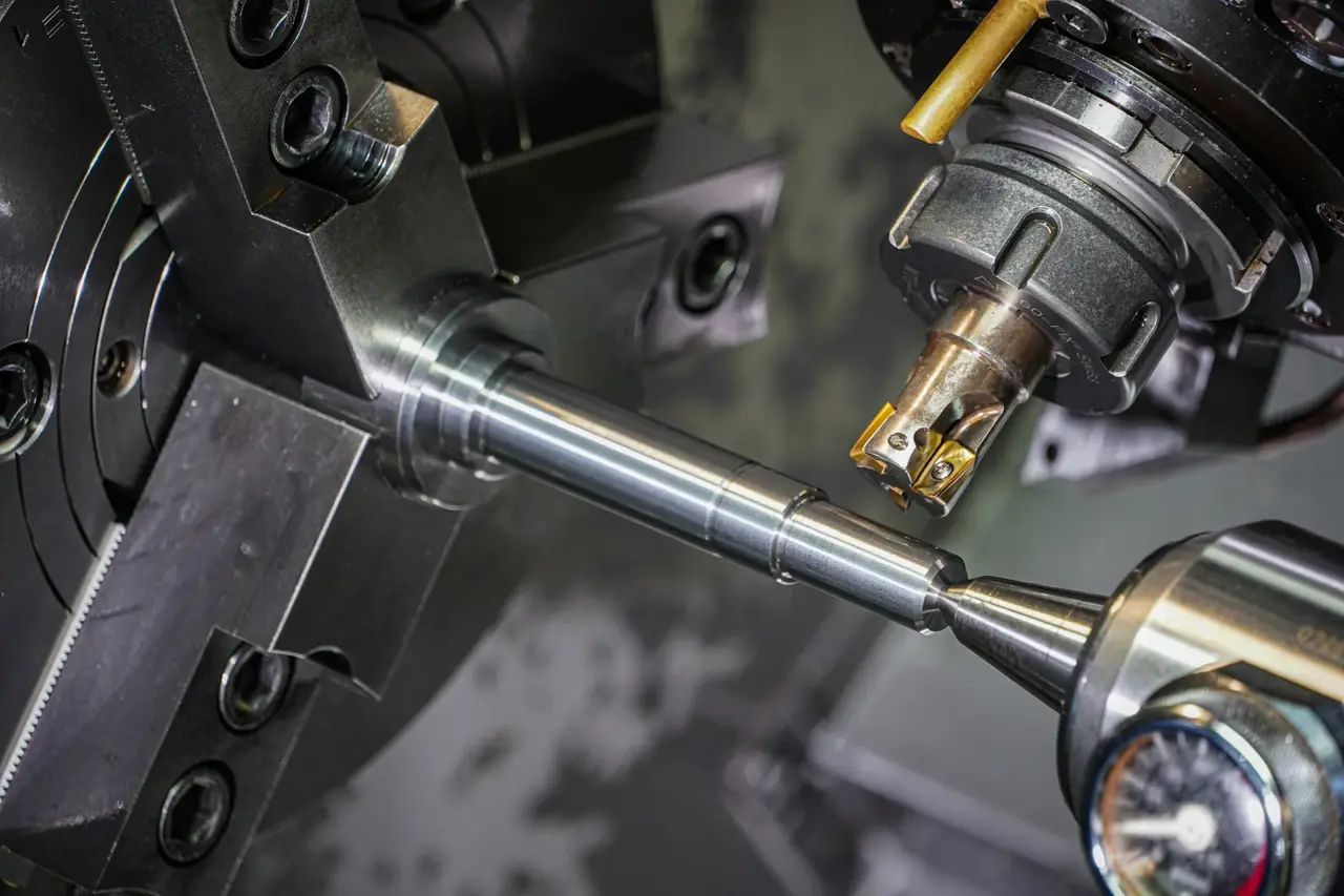 Barra de metal sujeta en el chuck de un torno CNC mientras la herramienta de corte la maquina